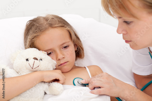 Photo: Sad little girl laying sick in bed Sad little girl laying sick in bed