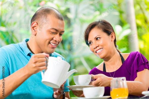 Photo: Asian couple having coffee on home porch Asian couple having coffee on home porch