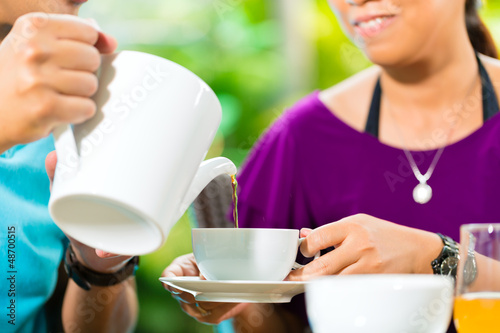 Photo: Asian couple having coffee on home porch Asian couple having coffee on home porch