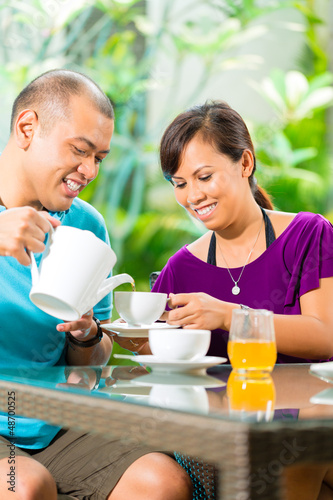 Photo: Asian couple having coffee on home porch Asian couple having coffee on home porch