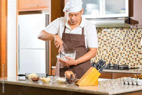 Photo: Asian man baking cake in home kitchen Asian man baking cake in home kitchen