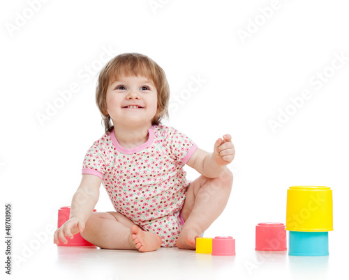 Photo: Funny little child is playing with toys while sitting on floor, Funny little child is playing with toys while sitting on floor,