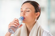 Photo: Portrait of young woman drinking water at gym after doing exerci Portrait of young woman drinking water at gym after doing exerci