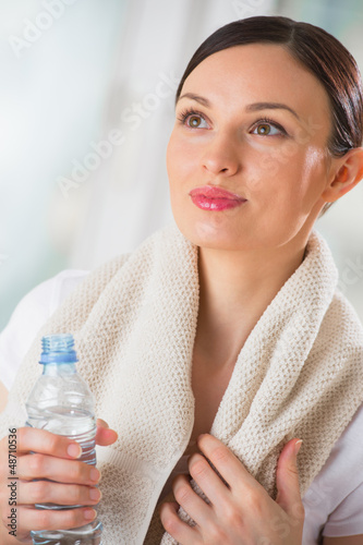 Photo: Portrait of confident young woman in sportswear holding a water Portrait of confident young woman in sportswear holding a water