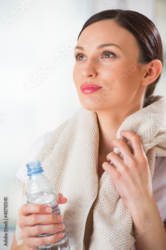 Photo: Portrait of confident young woman in sportswear holding a water Portrait of confident young woman in sportswear holding a water