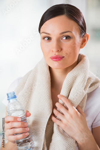 Photo: Portrait of confident young woman in sportswear holding a water Portrait of confident young woman in sportswear holding a water