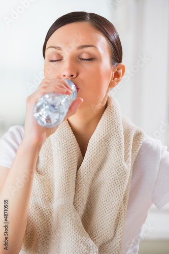 Photo: Portrait of young woman drinking water at gym after doing exerci Portrait of young woman drinking water at gym after doing exerci