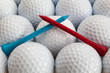 An closeup of a regular a blue and red golf tees on a golf balls