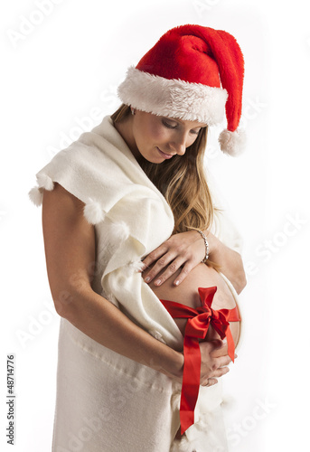 Photo: Smiling pregnant woman wearing santa hat isolated over white Smiling pregnant woman wearing santa hat isolated over white