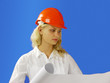 woman architect wearing a hardhat examining blueprints