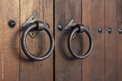 Photo: Old medieval metal handles on antique dark wooden door Old medieval metal handles on antique dark wooden door