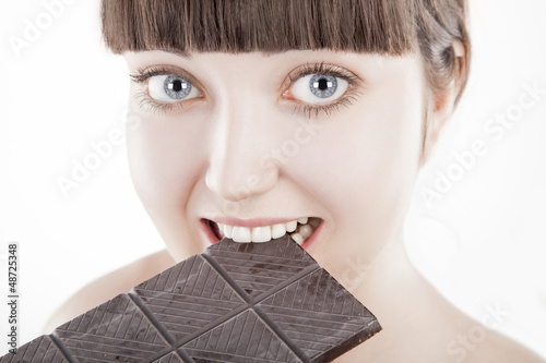 Photo: Beautiful young woman eating big chocolate bar Beautiful young woman eating big chocolate bar
