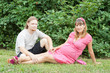 a happy young pregnant woman with her husband resting in a park