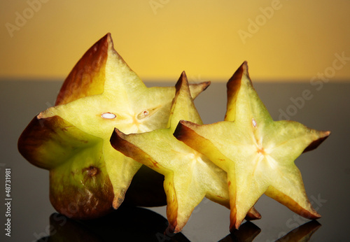 Photo: Two ripe carambolas on yellow background Two ripe carambolas on yellow background