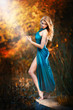 young women in a blue long dress at sunset in a forest