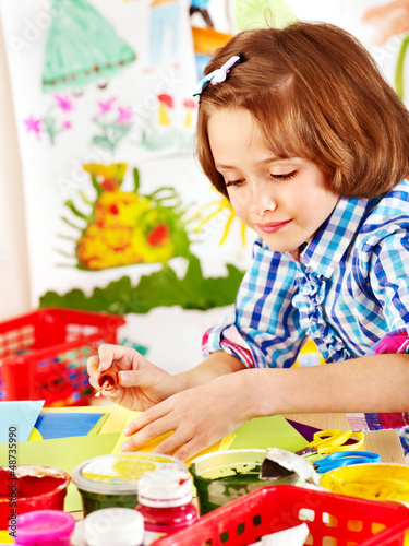 Photo: Child painting at easel. Child painting at easel.