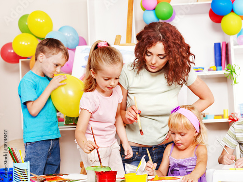 Photo: Child painting at easel. Child painting at easel.