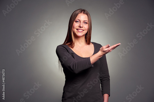 Photo: young woman pointing palm up young woman pointing palm up