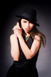 a beautiful brunette woman in black hat making a gun gesture