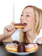 Foto: Pretty woman takes a bite of a donut with closed eyes Pretty woman takes a bite of a donut with closed eyes