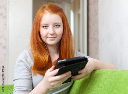 Photo: Teen girl reads e-reader or tablet computer Teen girl reads e-reader or tablet computer