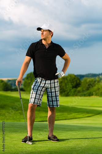 Photo: Young sportive man playing golf on a course Young sportive man playing golf on a course