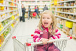 Photo: Adorable girl screaming in shopping cart in supermarket Adorable girl screaming in shopping cart in supermarket