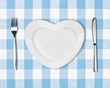 plate in shape of heart, table knife and fork on blue tablecloth