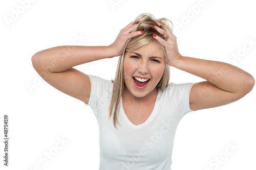 Photo: Young girl screaming loud while holding her head Young girl screaming loud while holding her head