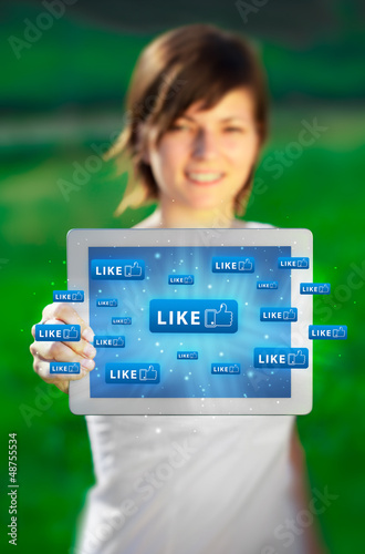 Photo: Young woman looking at modern tablet with abstract lights and so Young woman looking at modern tablet with abstract lights and so