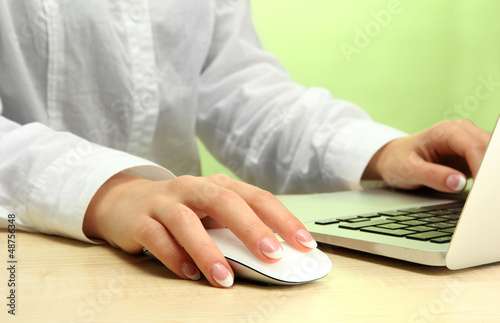 Photo: female hands writing on laptot, on green background female hands writing on laptot, on green background