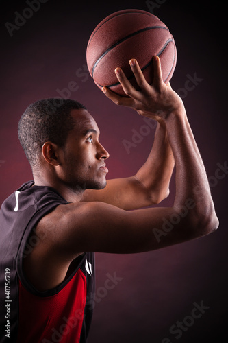 Photo: young male basketball player against black background young male basketball player against black background