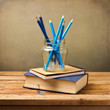Old vintage book, note book and blue pencils on wooden table