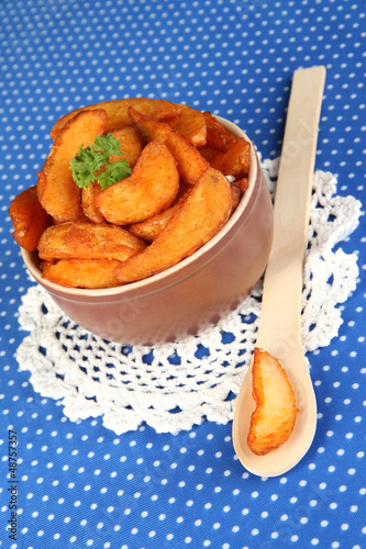 Photo: Appetizing village potatoes in bowl on blue fabric close-up Appetizing village potatoes in bowl on blue fabric close-up