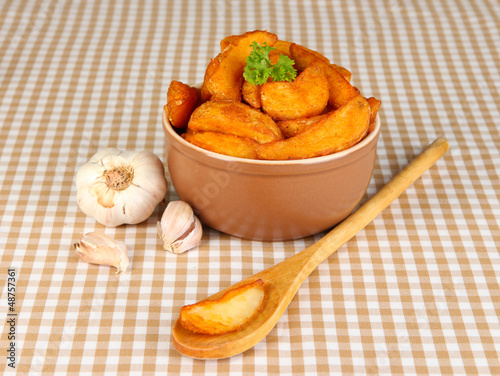 Photo: Appetizing village potatoes in bowl on beige tablecloth Appetizing village potatoes in bowl on beige tablecloth