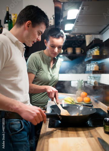 Photo: Young couple preparing lunch in kitchen Young couple preparing lunch in kitchen