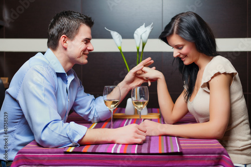 Photo: Young couple sitting in restaurant and flirting Young couple sitting in restaurant and flirting
