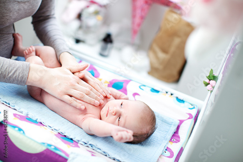 Photo: New born baby lying in bed caressed by mother New born baby lying in bed caressed by mother