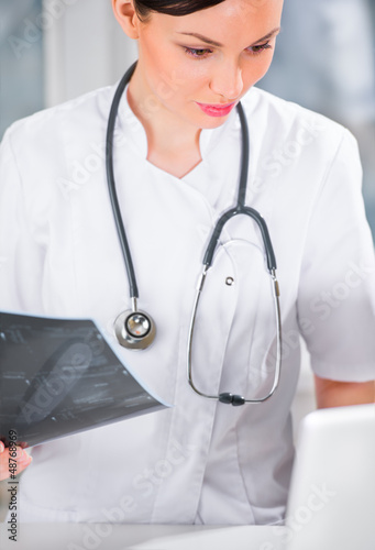 Photo: Portrait of a female doctor holding ultrasound results and using Portrait of a female doctor holding ultrasound results and using