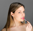 Attractive woman applying gloss on her lips