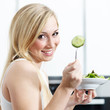 Pretty girl in the kitchen eating healthy food to lose weight