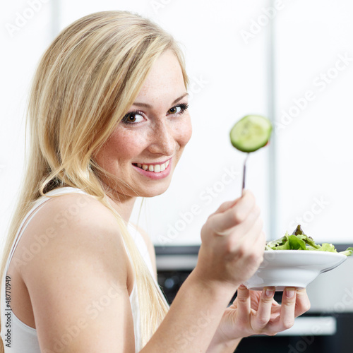 Photo: Pretty girl in the kitchen eating healthy food to lose weight Pretty girl in the kitchen eating healthy food to lose weight