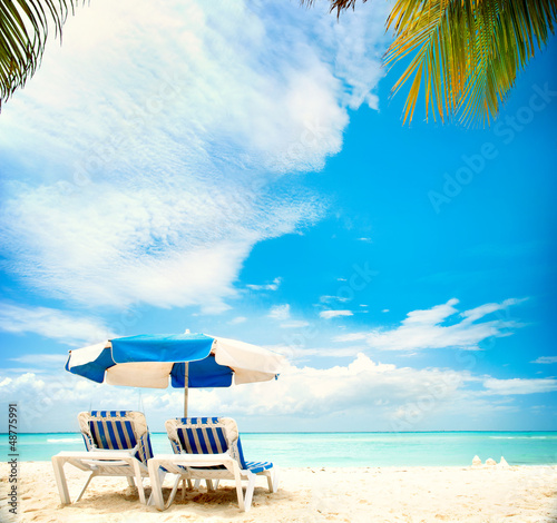 Photo: Vacation and Tourism concept. Sunbeds on the paradise beach Vacation and Tourism concept. Sunbeds on the paradise beach