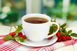 cup of tea with hip roses, on wooden table