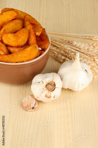 Photo: Appetizing village potatoes in bowl on wooden table close-up Appetizing village potatoes in bowl on wooden table close-up
