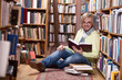 Handsome man reading book while sitting on floor in library