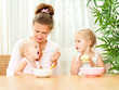 young mother feeding her two daughters from a spoon