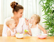 Photo: young mother feeding her two daughters from a spoon young mother feeding her two daughters from a spoon