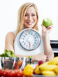 Foto: Girl with scale and fruits in kitchen is proud to lose weight Girl with scale and fruits in kitchen is proud to lose weight