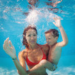 Mother and son having fun underwater in swimming pool.